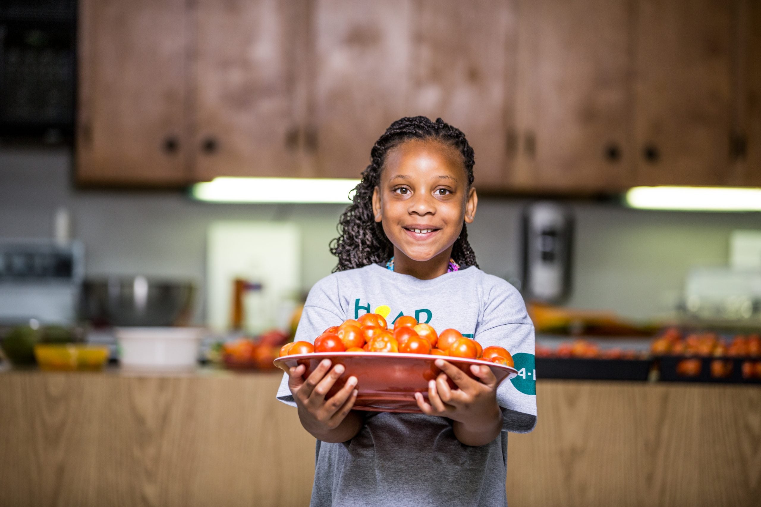 a girl holding a plate of tomatoes