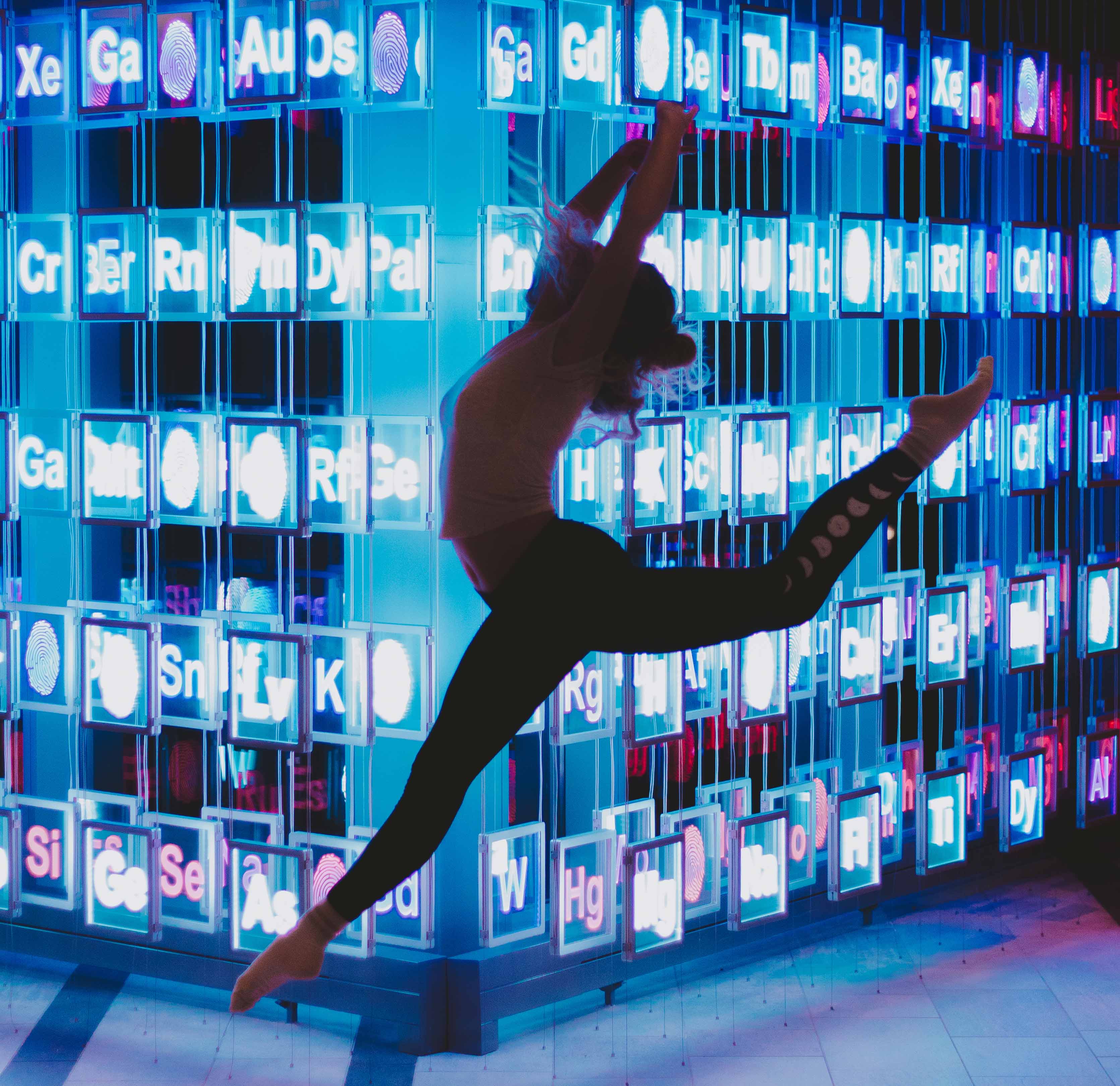 leaping dancer in front of illuminated periodic table