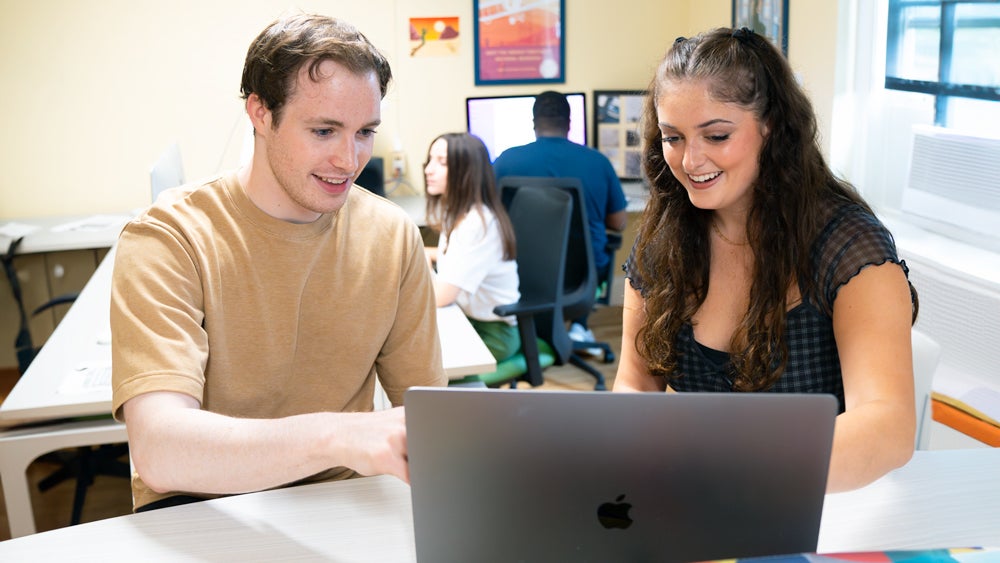 Two students working together at a computer in the Digital Writing Studio