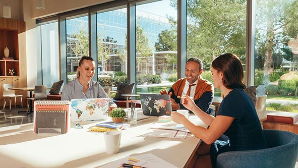 2 female and 1 male adult instructors sitting around a table in a conference room.