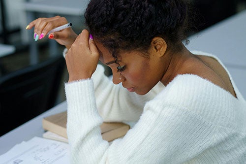 a female student seated at a desk, concentrating on an exam.