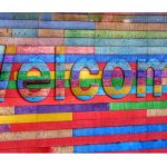 Welcome on a multicolored wooden background