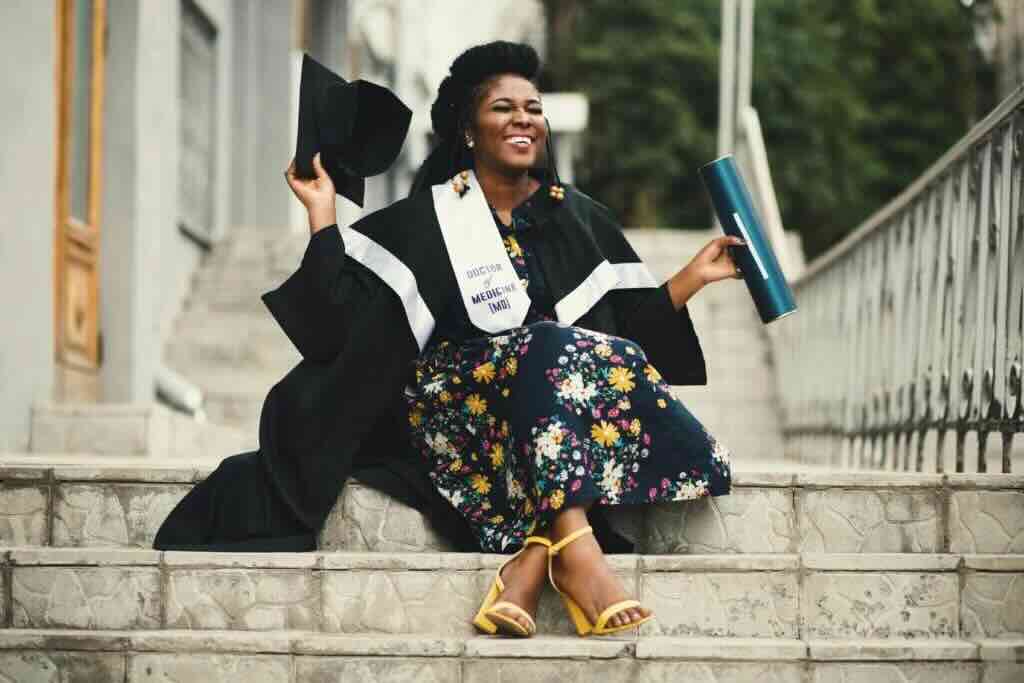 College graduate seated on the steps of a university building