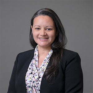 woman with short black hair smiling wearing black jacket and patterned shirt