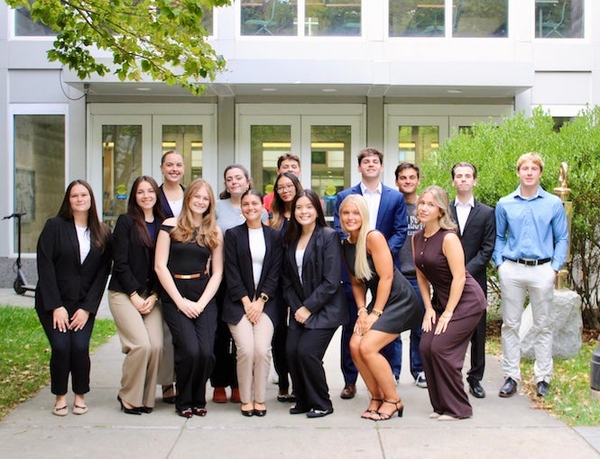 URI students stand in a group in front of Ballentine Hall on the URI Kingston campus.