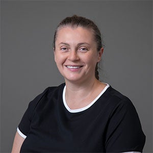 woman smiling wearing a black shirt with white trim at the neckline