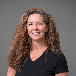 woman smiling with long curly brown hair, wearing a black shirt