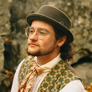 side profile of a URI TMD graduate student, wearing a hat, tie and glasses, with a beard