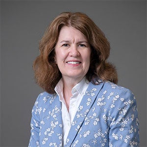 woman smiling wearing a white shirt and blue patterned blazer