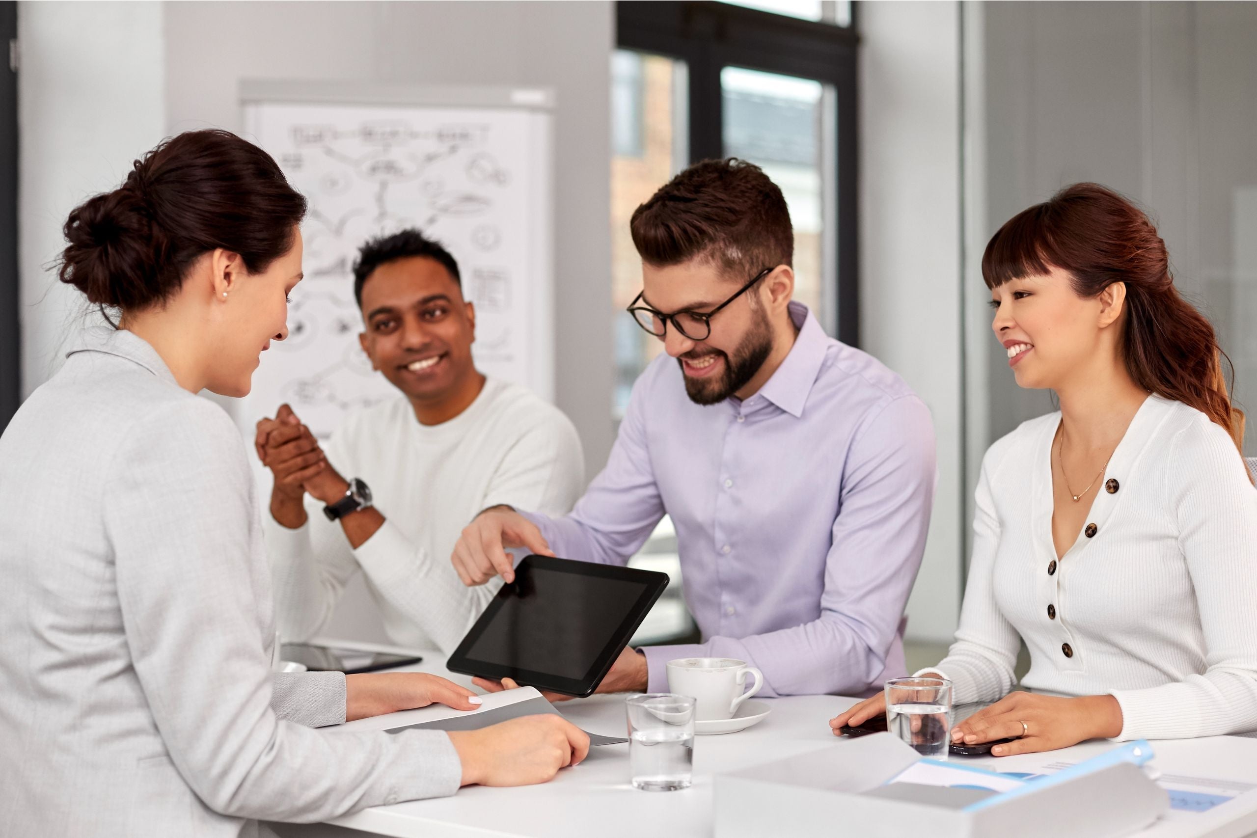 Group of students at a table talking and pointing to an ipad