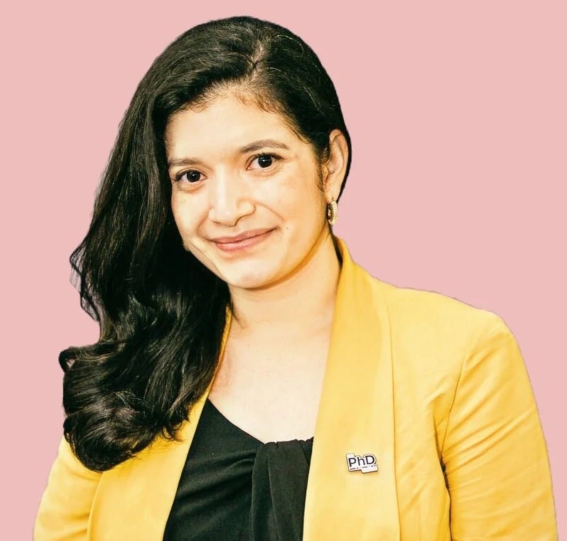 Priscilla Peña URI PhD student wearing a yellow blazer