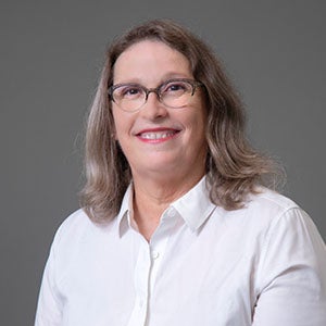 woman smiling wearing glasses and a white shirt