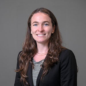 woman smiling wearing a stripped shirt and dark colored blazer.