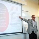 URI faculty member standing at the side of a presentation screen