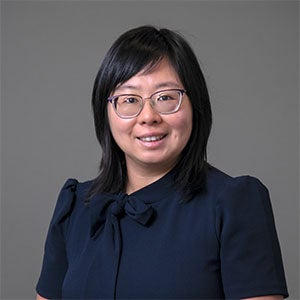 woman smiling wearing a dark blue shirt and glasses.