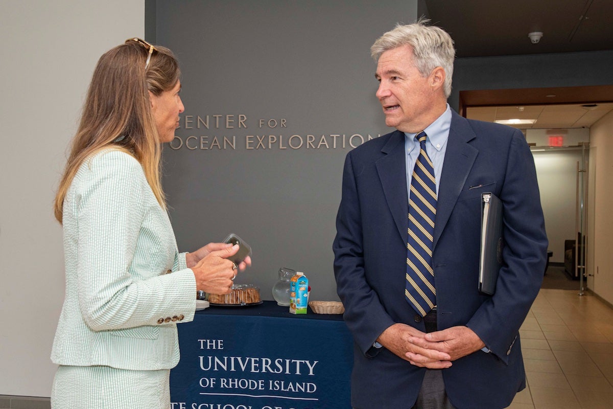 Senator Whitehouse and URI Dean is standing in front of a table talking