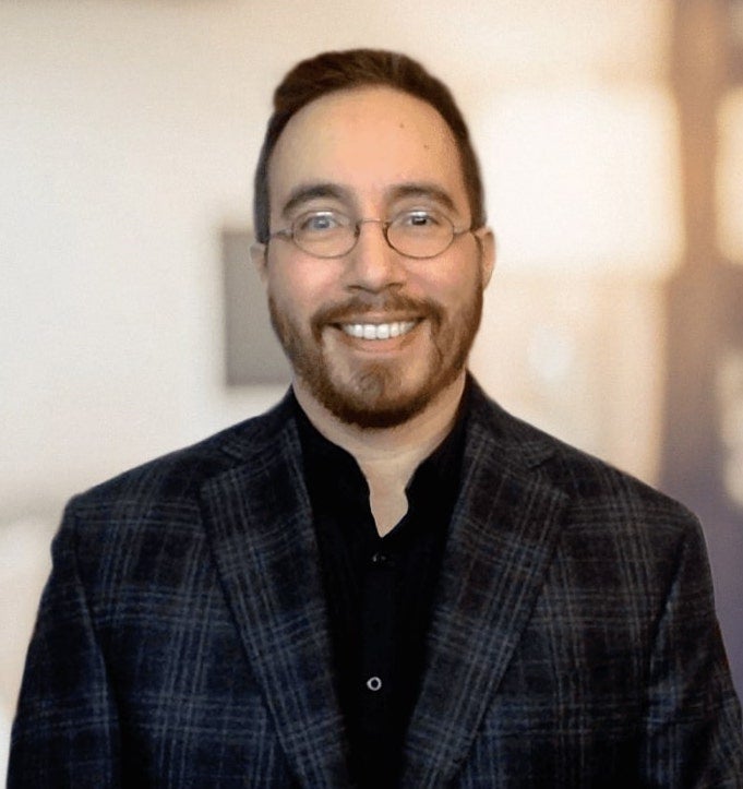 headshot of a man with a beard and mustache wearing glasses and smiling