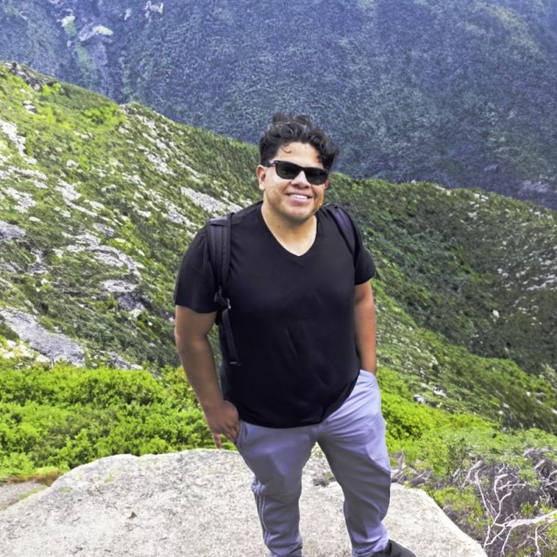 URI student standing on top of a rock with a valley behind him