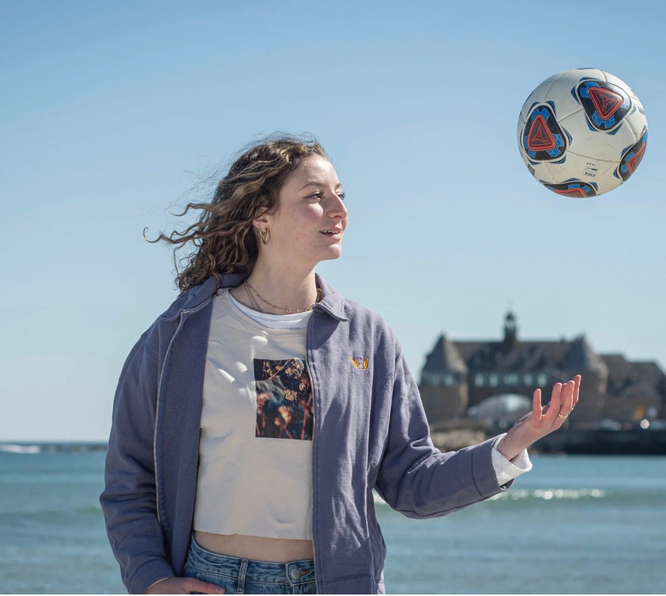 uri student tossing up a soccer ball with the ocean landscape in the background