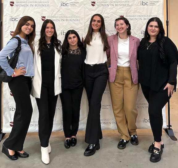 women gathered together, standing in front of a backdrop.