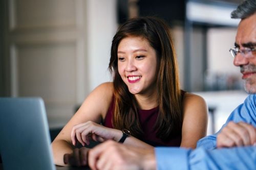a student sits with a mentor reading on a computer