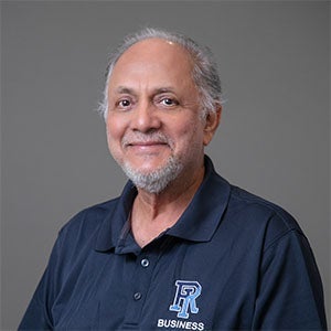 man smiling with white and gray short beard and hair, wearing a blue shorts sleeved shirt