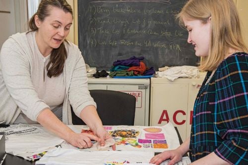 a professor helps a student with textiles