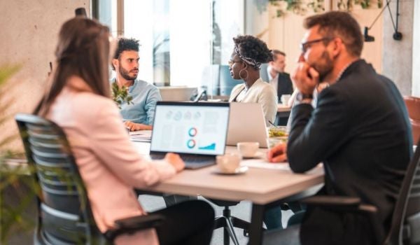 business and communications professionals sit at a working meeting