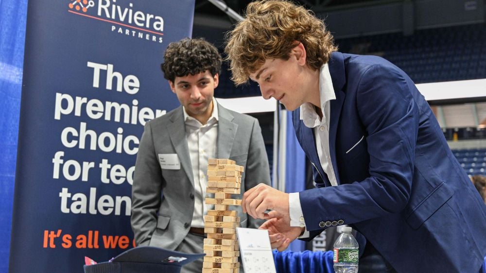 a business student plays jenga at a branded career fair table