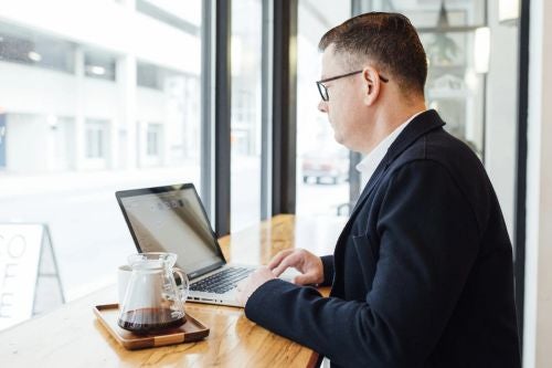 a man sits on a computer inside a coffee shop