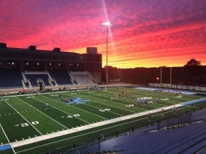 Meade Stadium with a fiery pink, orange, and yellow sunset in the background