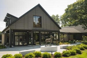 Robert J Higgins Welcome Center at URI on a sunny day. A ram statue sits in front of the building