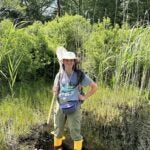 image of Abby Gall holding a butterfly net in a wooded area