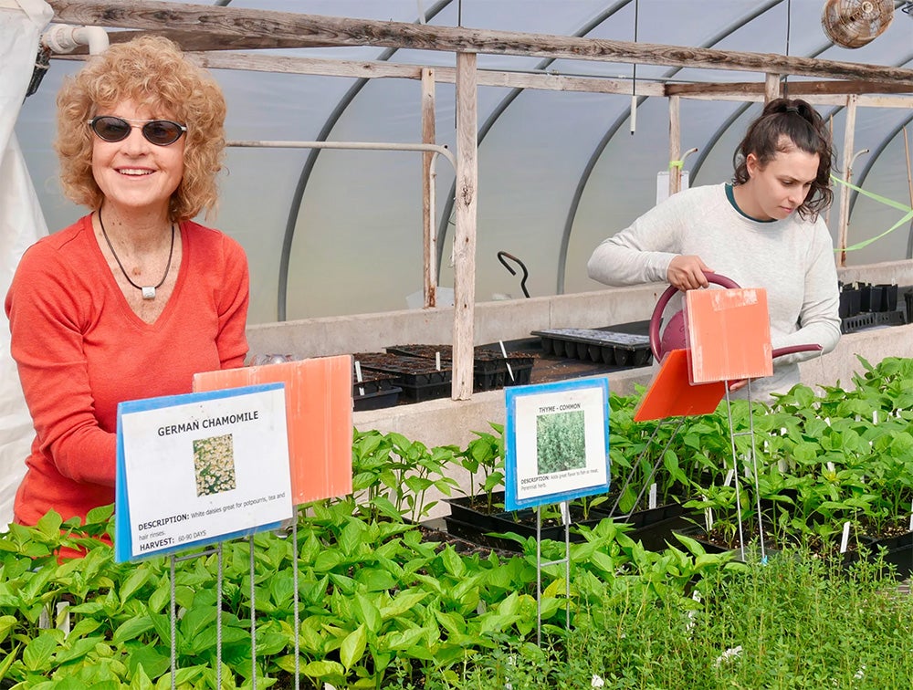image of two people smiling over trays of plants grown in URI's incubator program