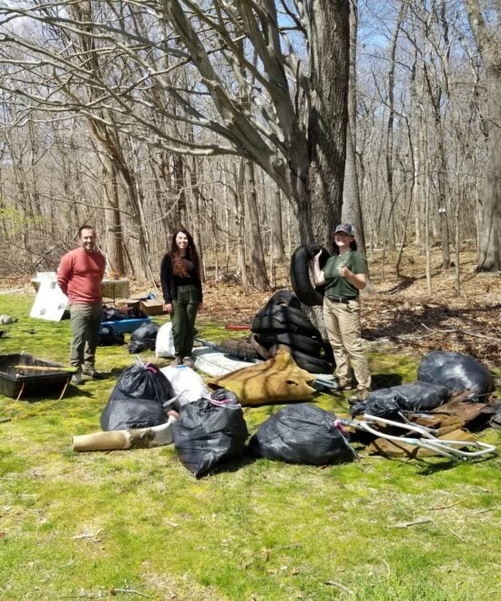Senior Lecturer Brett Still, graduate student Gabrielle Pezich, and Rachel Howard posing with the trash removed from the North Woods after our Earth Day 2022 Clean-up Event