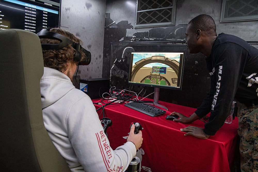 Ethan Sironen, a junior marine affairs major, left, tests his flying skills with a Marine Corps flight simulator as Marine Sgt. Thibault Adjogble looks on
