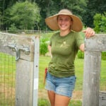 image of URI alumna Cassidy Need ’20 standing in the opening of a garden fence