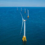 Image of offshore wind turbines in a row on yellow platforms.