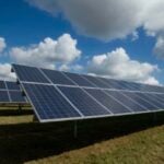 image of solar panels in a row under a blue and cloudy sky