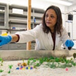 URI geosciences professor Soni Pradhanang demonstrates with her emulated river table, that offers a fun, hands-on way for K-12 students and local policymakers to learn about water issues and better visualize water’s impact on communities.