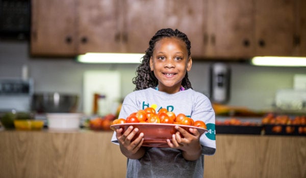 A young girl wearing a 4H tshirt holds a plat of tomatoes
