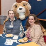 image of two people posing with URI's mascot, Rhody the Ram in full ram costume