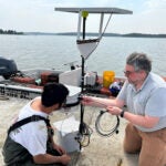 Dave Brown, at right, URI research associate, works on a laser "scarecrow" device with an oyster grower on a platform in Barnstable, Massachusetts. Photo courtesy of Rebecca Brown.