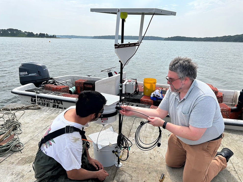 Dave Brown, at right, URI research associate, works on a laser "scarecrow" device with an oyster grower on a platform in Barnstable, Massachusetts. Photo courtesy of Rebecca Brown.