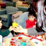 A preschool student from the URI Child Development Centers hands a candle holder to a paying customer. The students sold their custom artwork to benefit the RI Community Food Bank.