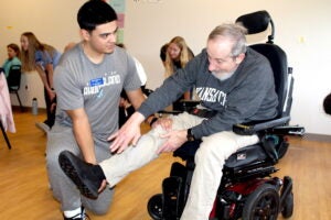 HELPING HAND: Adrian Franco, a doctor of physical therapy student at URI, helps out a participant at the Parkinson’s Exercise Group. URI photo by Patrick Luce.