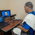 Former Communications Disorders student Marland Chang demonstrates the eye-tracking and EEG technology used in a URI study on audio-visual speech perception.
