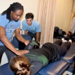 University of Rhode Island physical therapy students practice working with clients in a mock lab classroom. The graduate students, under faculty supervision, help staff the URI Physical Therapy Clinic, which is open to the public and the URI community.