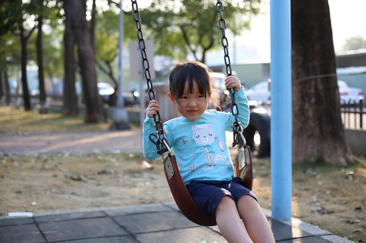 girl playing on playground swing