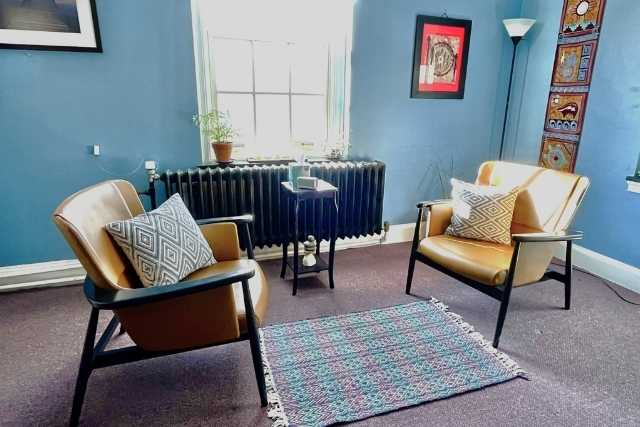 Therapy room with two chairs, blue walls, and a blue and white rug